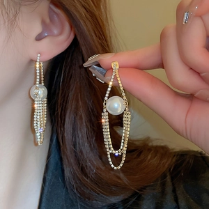 Close-up of gold dangle earrings with pearls and crystal rhinestones on model