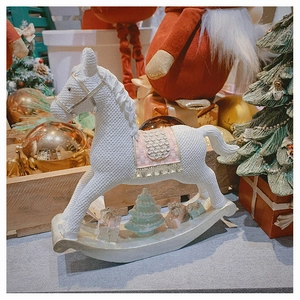 Detail of a white resin rocking horse with woven texture and festive Christmas ornaments