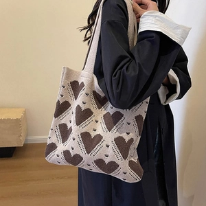 Close-up of heart pattern on beige knitted tote bag with focus on knit texture