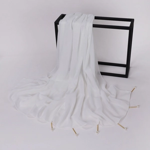Detail of white chiffon shawl with gold metal pins and pearls on a black display stand