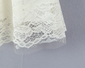 Close-up of layered white lace patterns and delicate mesh fabric on the dress hemline