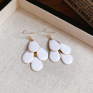 Macro detail of multi-layered white teardrop tassel earrings on a vintage display