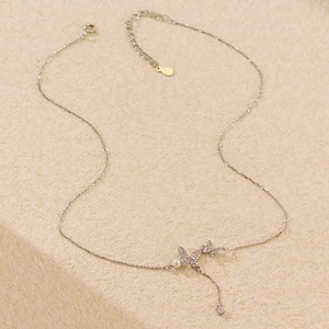 Macro detail of silver butterfly necklace with tassel pearl and sparkling rhinestones