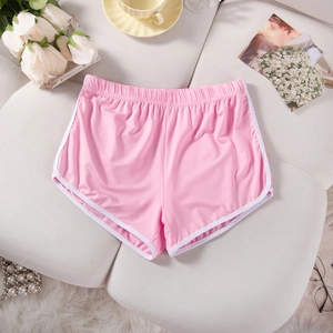 Detailed flat lay of pink athletic shorts with white piping on a cozy sofa background