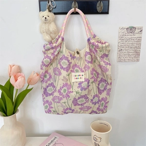 Detailed shot of floral canvas tote bag featuring colorful braided rope handles and logo
