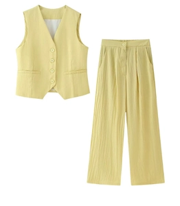 Détail de la texture du gilet jaune à col en V et du pantalon large en aspect lin