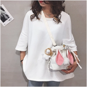 Close-up of white canvas bucket bag featuring cute rabbit ears and decorative badges