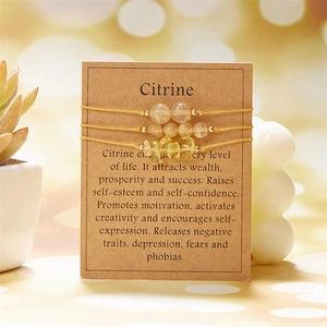 Three citrine bracelets with natural stones on kraft paper card against bokeh background