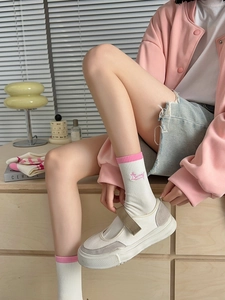 Close-up of pink ribbed cuffs on white socks with cute embroidery and Mary Jane shoes