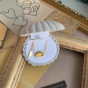 18K gold Virgin Mary pendant necklace displayed in a shell-shaped velvet jewelry box