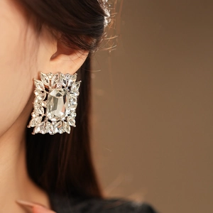 Close-up of a luxury square crystal earring with marquise stones on a model ear