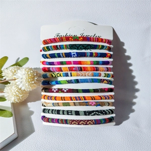 Detailed view of 12 handmade colorful woven bohemian style bracelets on white card display