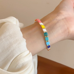 Close-up of colorful square beaded bracelet with gold spacers on a female wrist
