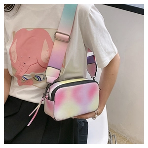 Detail shot of gradient pastel camera bag with wide shoulder strap worn by a model