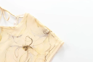 Détail de robe longue licou jaune clair avec imprimé fleuri et nœud délicat au cou