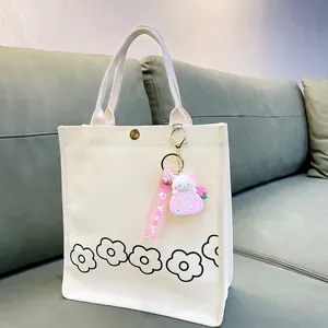 Cute cartoon cat swiss roll cake keychain charm on a white minimalist canvas handbag