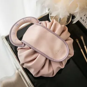 Detail view of pink drawstring makeup bag featuring PU handle and Tea Break logo