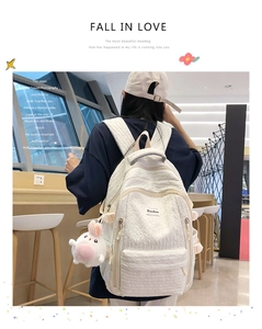 Détail du sac à dos blanc en tissu gaufré avec multi-poches et pendentif en peluche