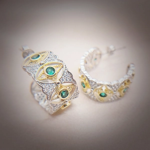 Macro detail of vintage two-tone gold earrings with green emerald and white zircon