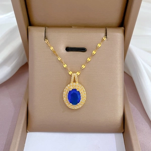 Détail d'un collier en or avec pierre bleue ovale et diamants dans un écrin à bijoux