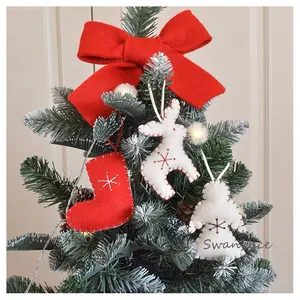 Red wool felt Christmas stockings and white deer ornaments with red bow on pine branch