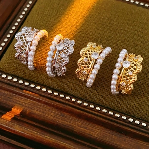 Detail view of vintage pearl rings with zircon insets on green velvet tray