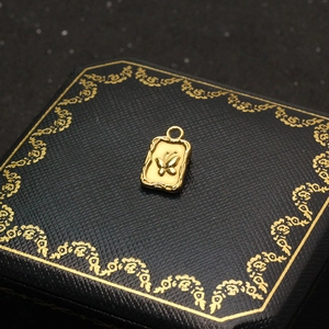 Detailed view of a gold butterfly rectangle pendant on a luxury black jewelry box