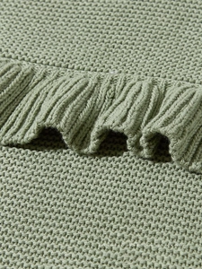 Macro shot of sage green knit baby blanket showing ruffle edge and grainy weave texture