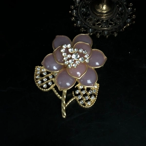 Detail der rosa Blumenbrosche mit Goldbeschichtung und Strasssteinen auf schwarzem Samt