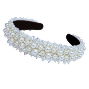 Elegant wide headband with white faux pearls and crystals on a minimalist white background