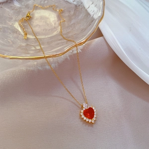 Detailed view of a gold-tone necklace featuring a red heart pendant with pave crystals
