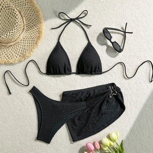 Flat lay of black seersucker 3-piece bikini set with matching sarong and summer accessories