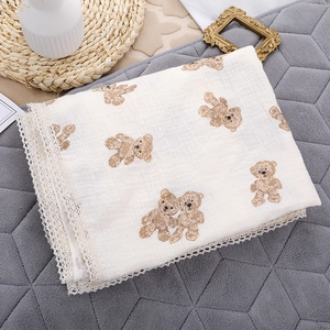 Detail of baby muslin swaddle with delicate lace edges and cute brown bear print patterns