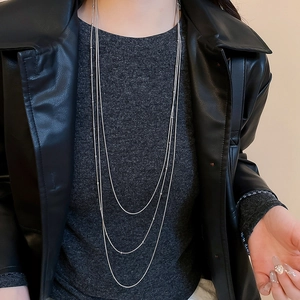 Detail of layered silver tassel necklace with small beads worn over black jacket