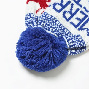 Close-up of a blue fluffy pom-pom and knitted texture on a white Christmas beanie