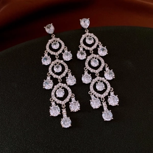 Close-up of chandelier earrings with round and teardrop zircons in silver plating