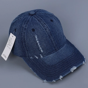 Detailed macro view of distressed denim baseball cap with vintage frayed edges and texture
