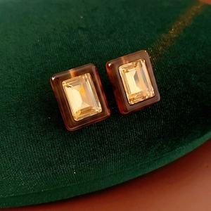 Macro shot of rectangular resin stud earrings with faceted amber yellow crystals