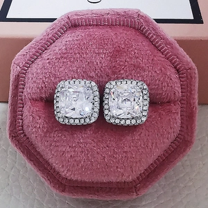 Macro shot of square-cut zircon stud earrings in silver on pink velvet jewelry box