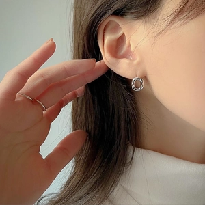 Minimalist 925 sterling silver twisted hoop earrings worn on ear with polished finish