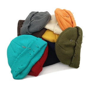 Distressed knit beanies with safety pins and ripped details in multiple colors