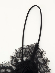 Détail de robe en dentelle noire avec bordure en cils et fines bretelles réglables sur fond blanc