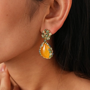 Gros plan sur les boucles d'oreilles fleur vintage avec pierre orange et détails en cristal