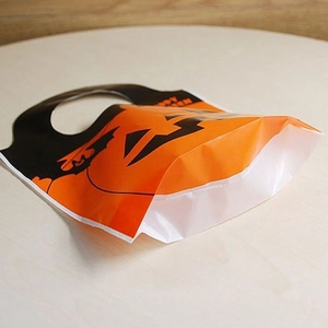 Orange Happy Halloween pumpkin tote bags with handles on a light wood background