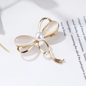 Detailed view of a gold bow brooch with champagne cat eye stones and a pearl center