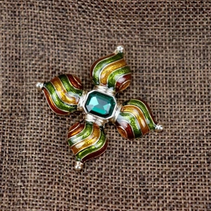 Makrodetail einer Vintage-Brosche im Hofstil mit grünem Edelstein und Emaille