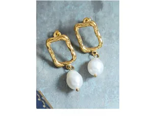 Detail of irregular gold earrings with hammered texture and baroque pearl pendants