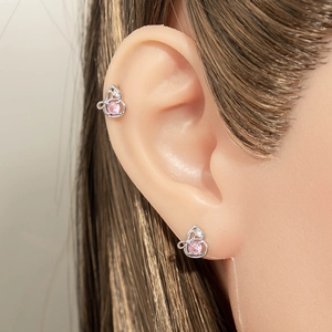 Silver bow-shaped titanium steel ear studs with pink gemstones on human model's ear