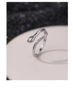 Detail of S925 sterling silver snake ring with green zircon eyes on a display stand