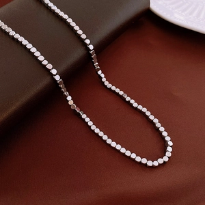 Detailed macro view of a silver stainless steel bead chain on a textured dark background